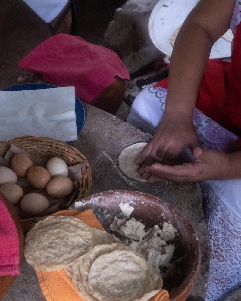 Manos dando forma a una tortilla de maíz sobre una mesa tradicional